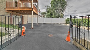 A gated parking area with a covered walkway and a building with a balcony. - Yonkers Apt w/ Balcony: Walk to Train Station! (Yonkers)