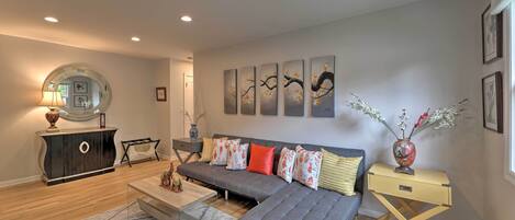 A modern living room with a grey sofa, a wooden coffee table, and a small side table with a vase.