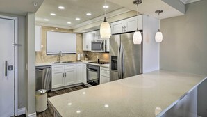 A modern kitchen with white cabinets, stainless steel appliances, and pendant lighting. - Waterfront Resort Condo w/ Private Beach & Pool (Hudson)
