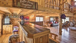A rustic log cabin interior with a bar area, leather furniture, and antler decorations. - Secluded Belle Fourche Cabin: Group Friendly! (Belle Fourche)