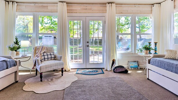 A cozy room with a large window, a sofa, a chair, and a bed. - Ocean Springs Home w/ Fire Pit & Game Room! (Biloxi)