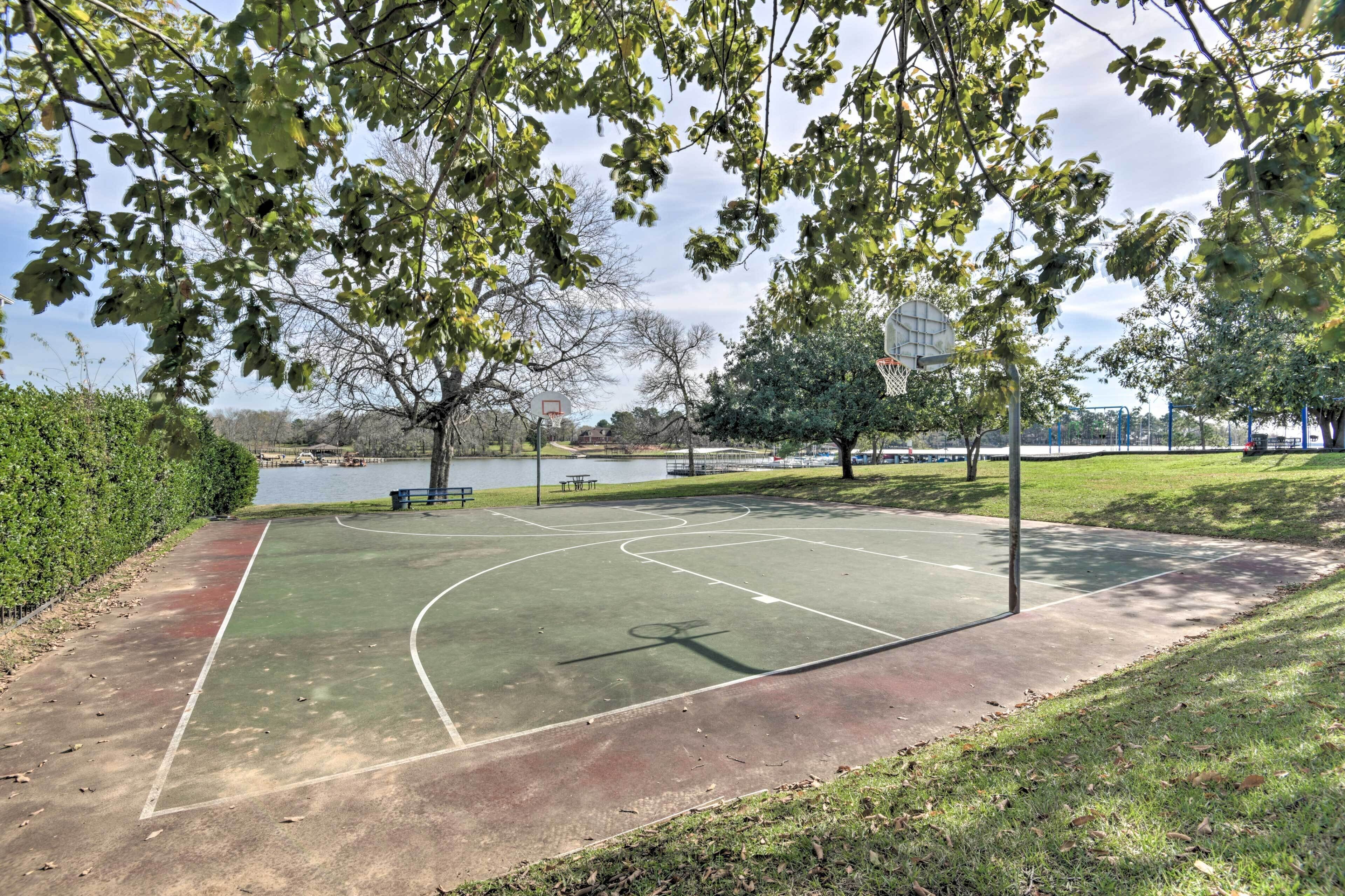 An outdoor basketball court with a view of a lake and trees in the background.