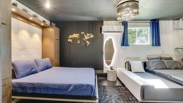 Ein modernes Hotelzimmer mit einem großen Bett, einer Schlafcouch, einer Wanddekoration mit Weltkarte und einer Deckenleuchte.