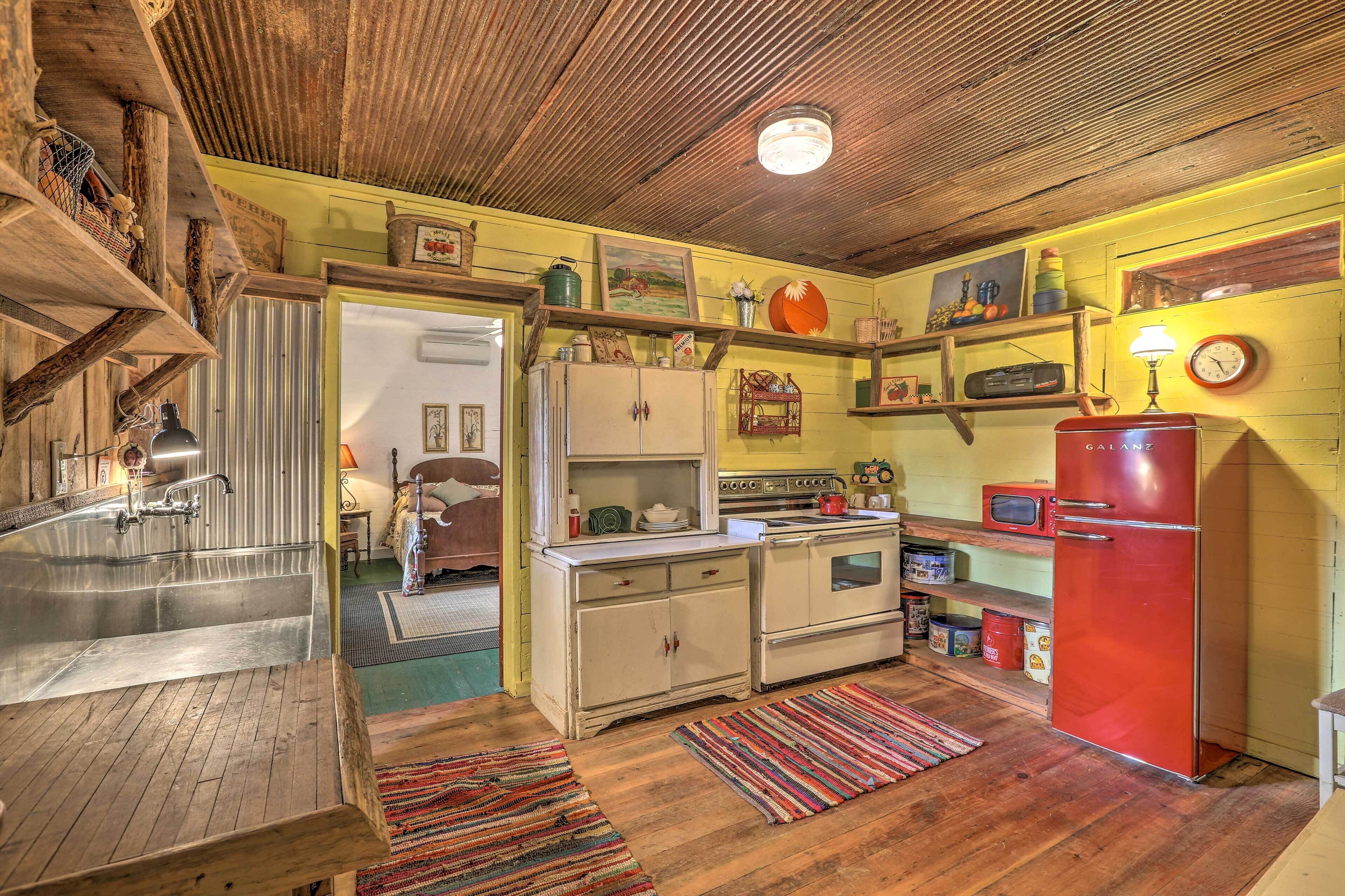 A rustic kitchen with wooden cabinets, a vintage refrigerator, and a sink.