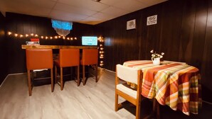 A bar area with wooden chairs, a bar counter, and a television screen. - Fantastic Oasis Home in Stevens Point with fully enclosed fence for backyard! (Stevens Point)