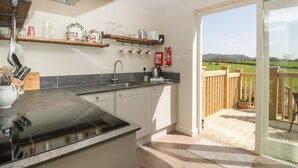 Una cocina moderna con estufa integrada, un lavamanos y ventana con vista a un campo cubierto de césped.