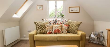 A cozy living room with a sofa, a coffee table, and a window with a view.
