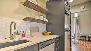 A modern kitchen with a built-in dishwasher, stainless steel appliances, and wooden shelves above the sink. - Cozy Lake Geneva Retreat With Year-round Views! (Lake Geneva)