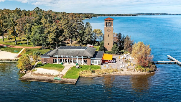 A lakeside building with a clock tower, surrounded by trees and a dock. - Pet-friendly Loft Vacation Rental w/ Fire Pit! (Bemus Point)