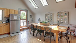 A kitchen with wooden cabinets, a stainless steel refrigerator, a dining table with chairs, and skylights. - Pet-friendly Loft Vacation Rental w/ Fire Pit! (Bemus Point)
