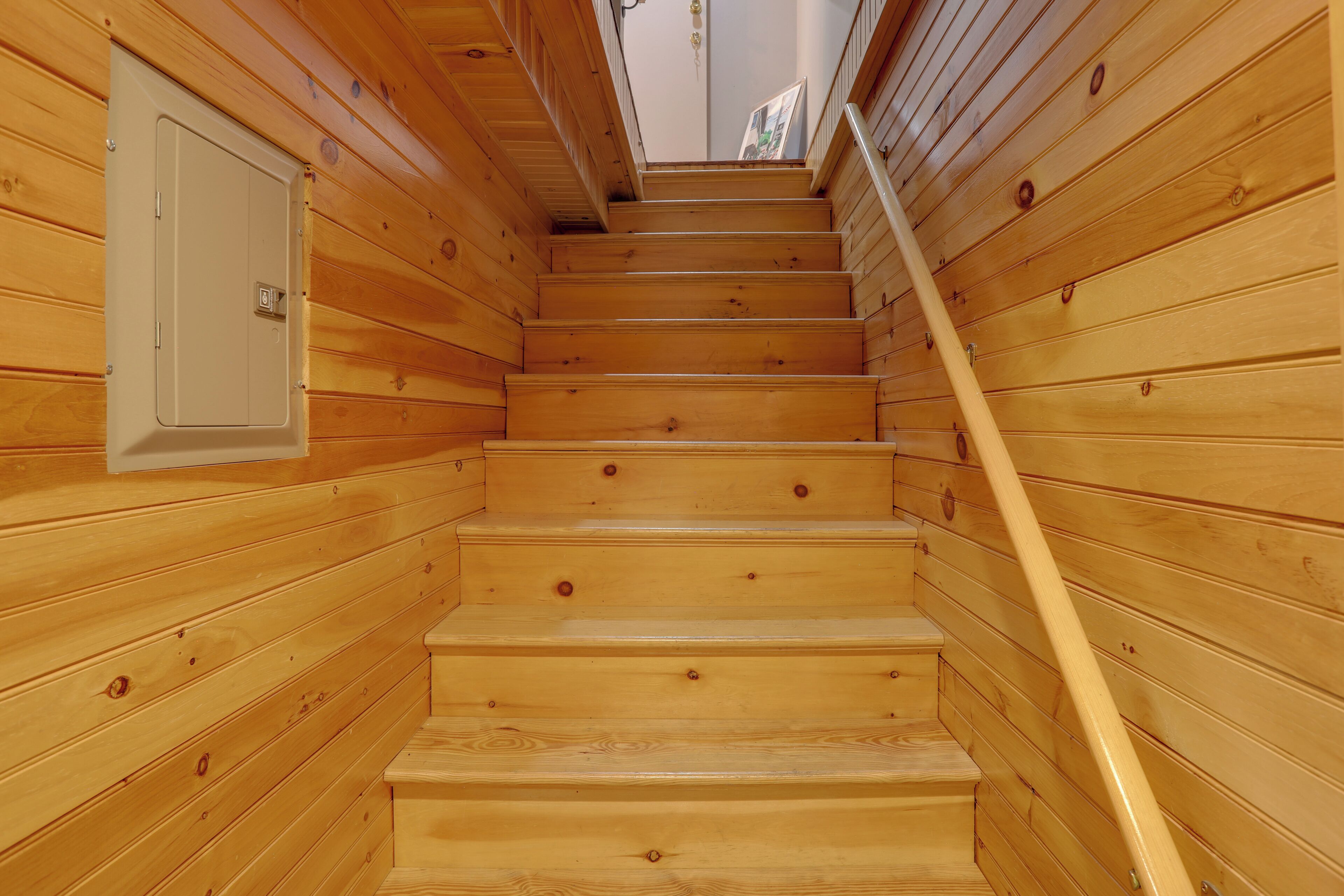 Una escalera de madera con barandilla que lleva a una puerta con un pequeño ventanal.