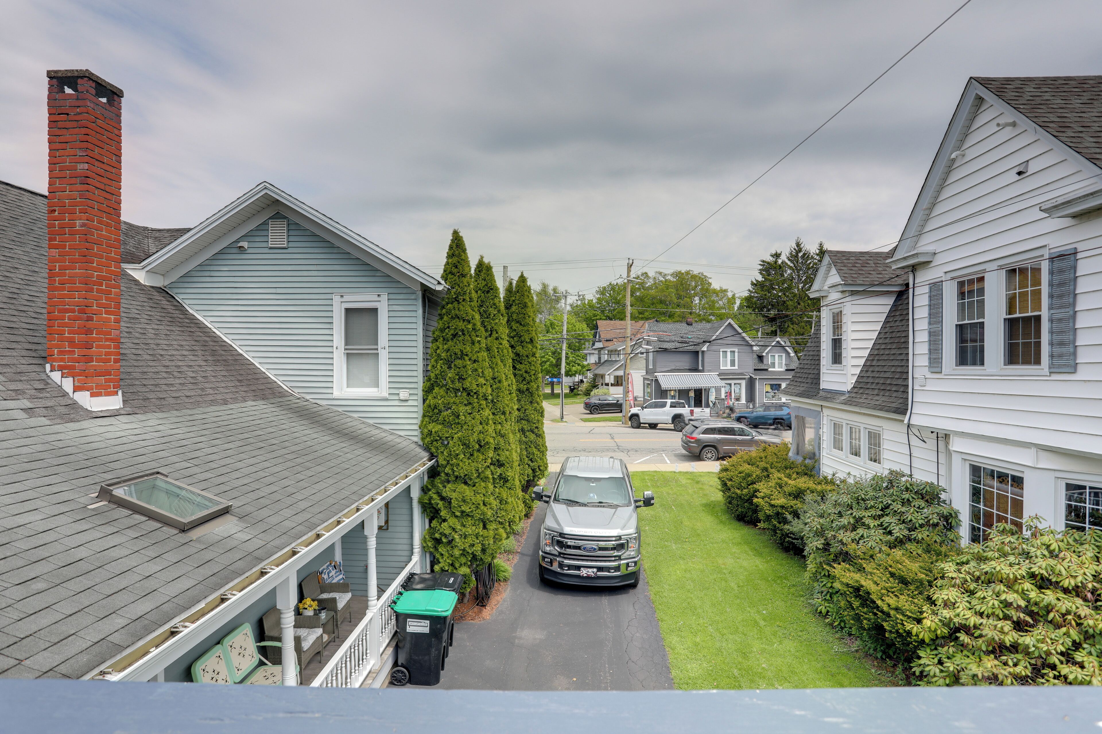 A residential street with houses, a truck, and a clear sky.