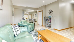 A living room with a light green sofa, a wooden coffee table, and a bookshelf. - Lake Mills Retreat: 1 Mi to Beaches & Dining! (Lake Mills)