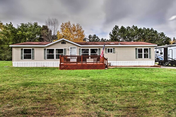 A single-story mobile home with a front porch and an American flag.