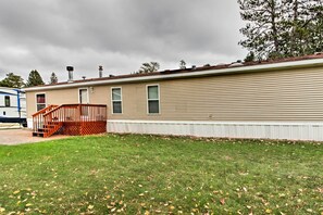 A single-story mobile home with a covered porch, a small attached garage, and a grassy yard.