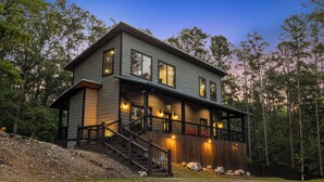 A two-story house with a covered porch and a staircase leading to the upper level.