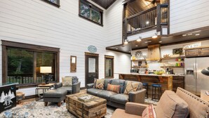 A spacious living area with a large sofa, a coffee table, and a kitchen in the background.