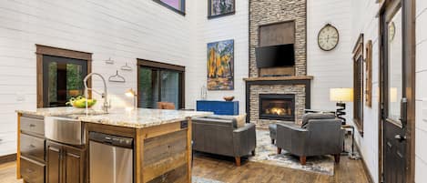 A spacious living area with a fireplace, a kitchen with a dishwasher, and a stone accent wall.