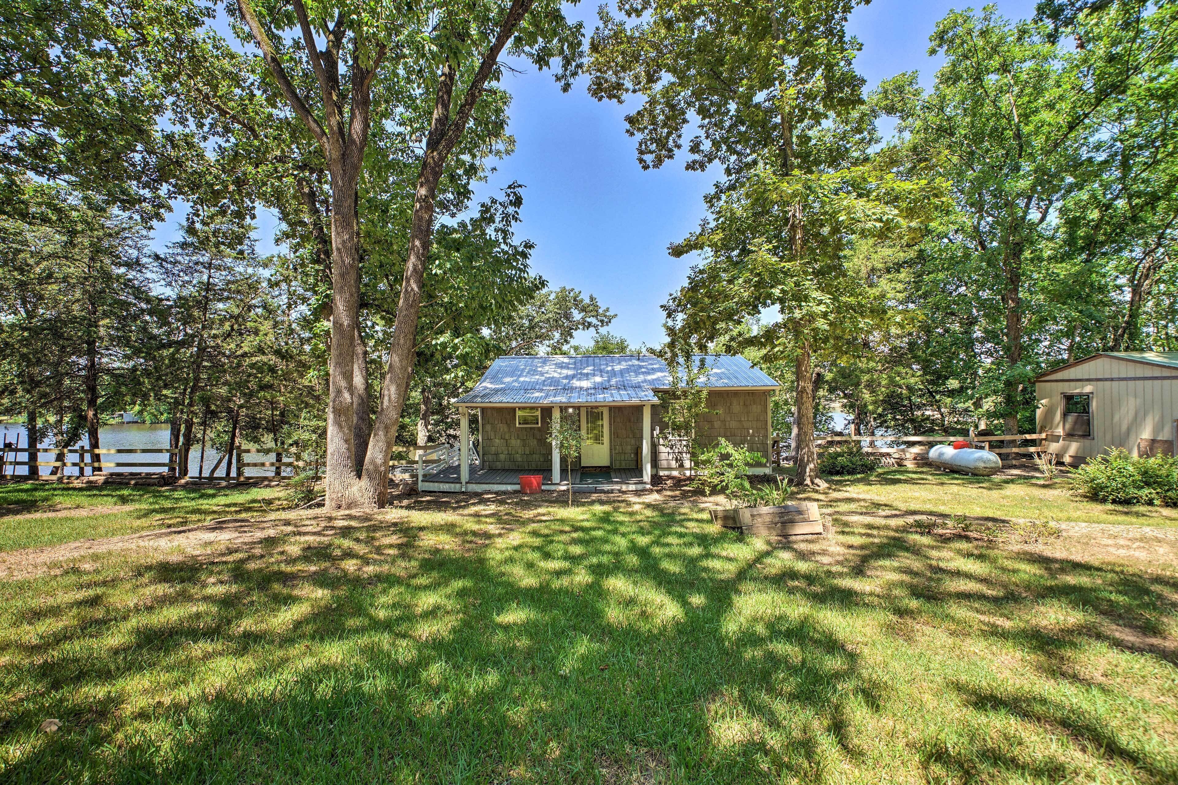 A house with a covered porch, a fenced yard, and a lake in the background.
