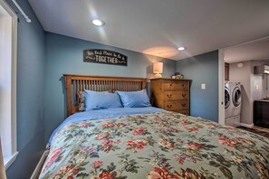 Une chambre à coucher avec une couvre-lit à motifs floraux, une tête de lit en bois, une commode et un panneau décoratif mural.