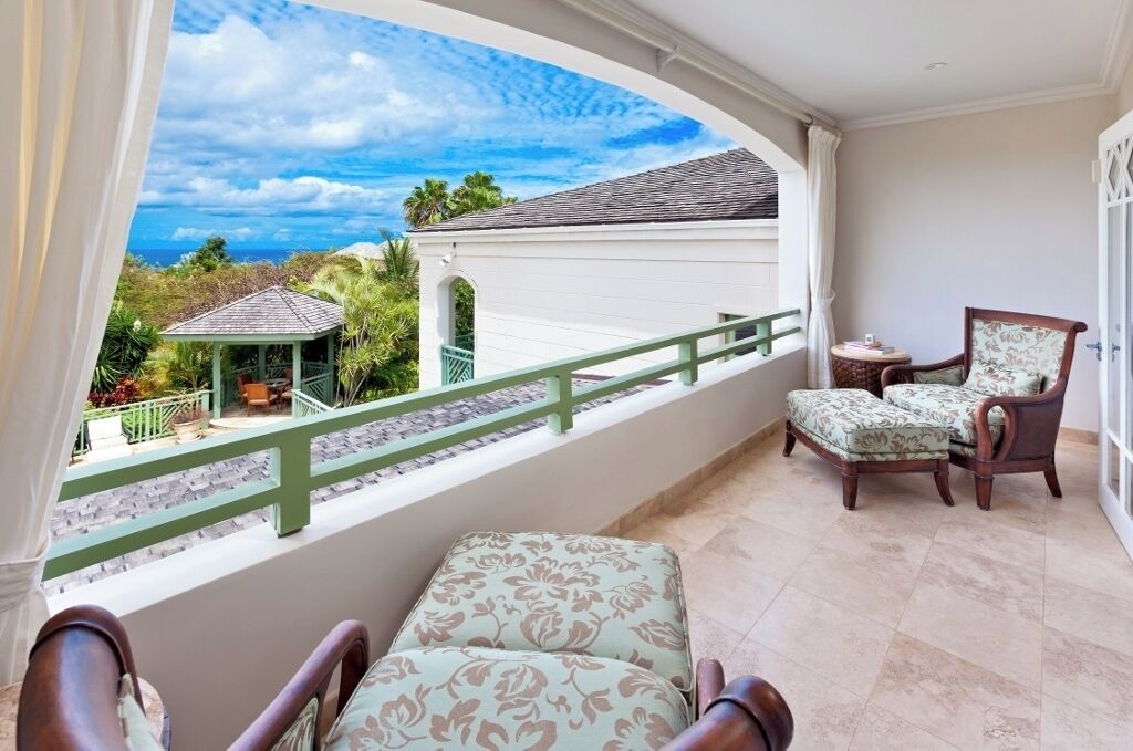 A balcony with a view of a gazebo, a chair, and a small table.
