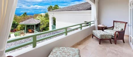 A balcony with a view of a gazebo, a chair, and a small table.