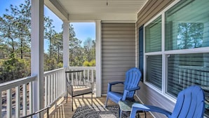 A covered porch with a view of trees, a blue chair, and a table. - Ocean Isle Beach Escape - Centrally Located! (Ocean Isle Beach)