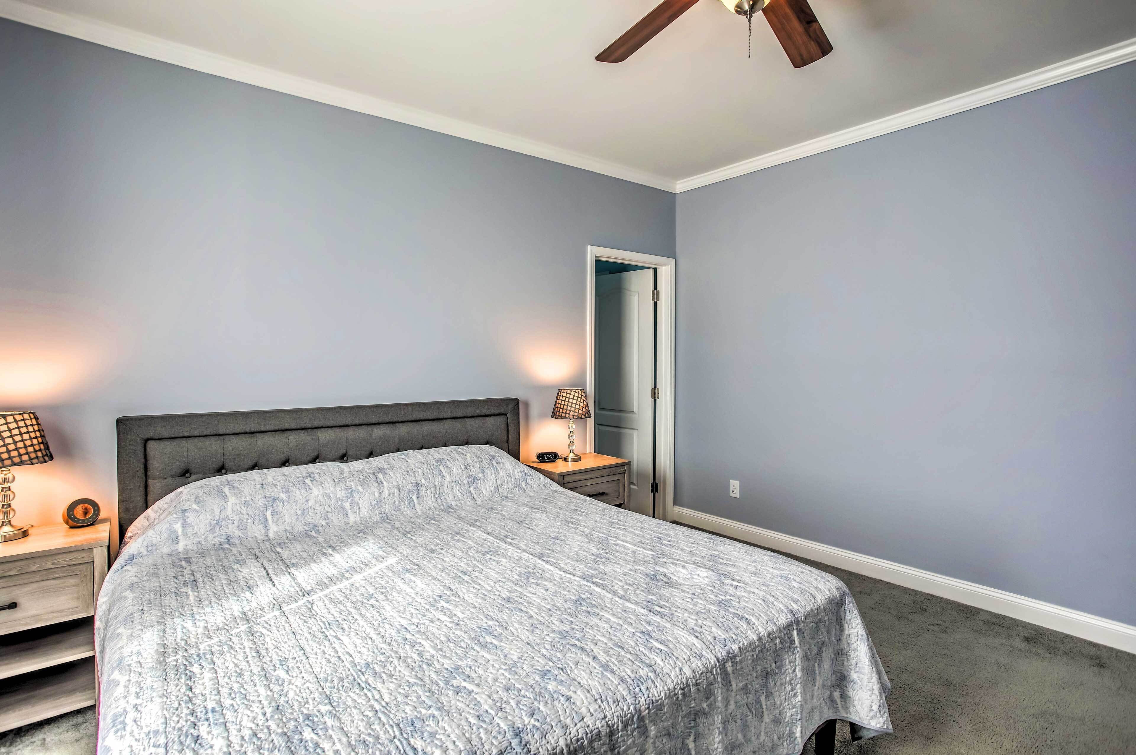 A bedroom with a bed, nightstands, a lamp, and a ceiling fan.