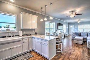 A modern kitchen with white cabinets, a marble countertop, and pendant lighting.