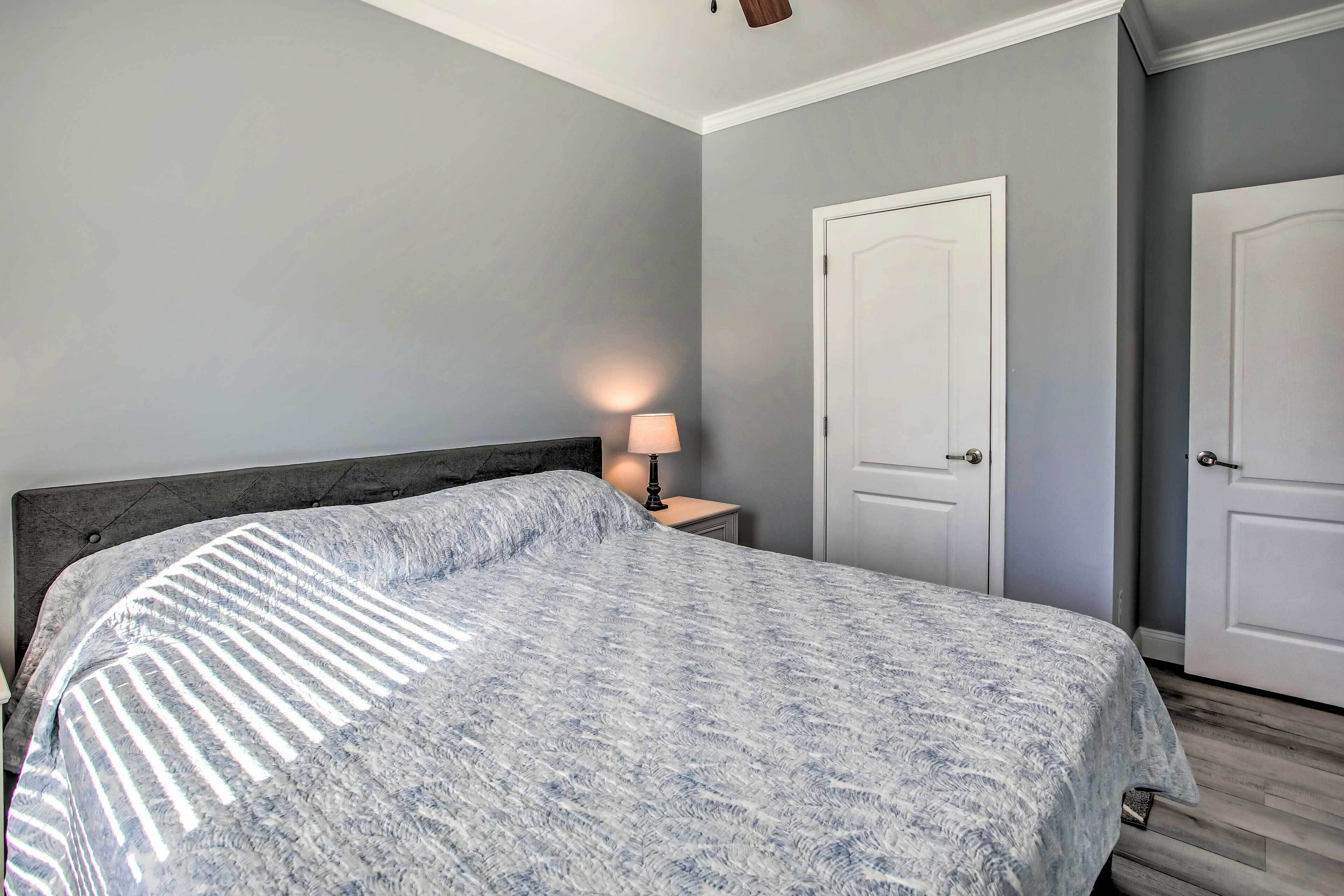 Une chambre à coucher avec un lit, une table de chevet, une lampe et deux portes.