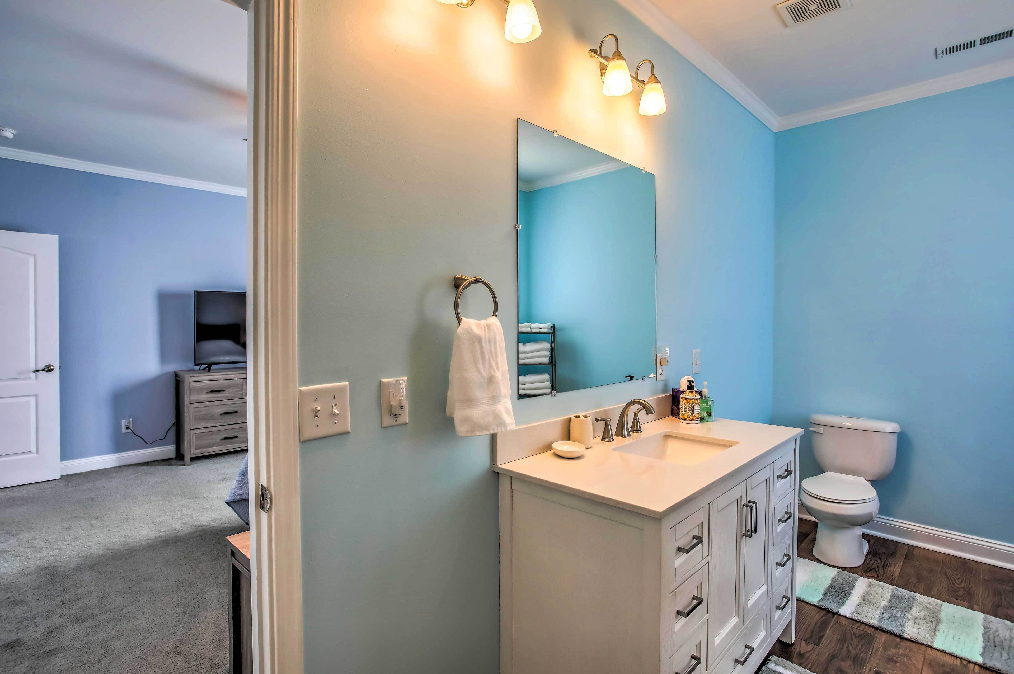 Une salle de bain avec un mur bleu, un lavabo blanc et un miroir.