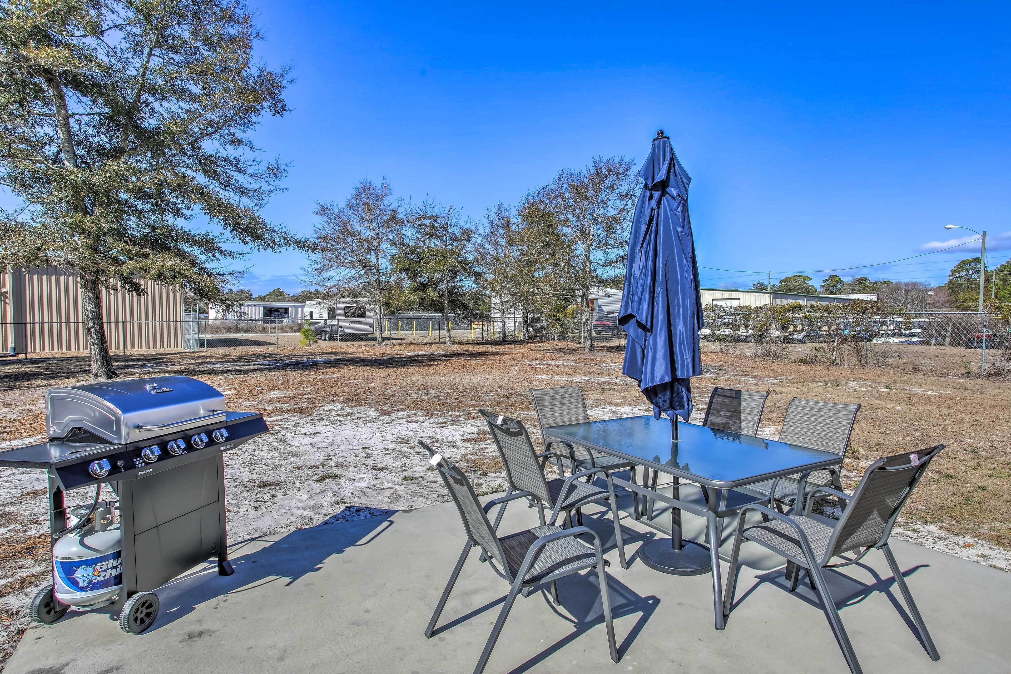 An outdoor patio with a grill, table, and chairs.