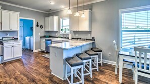 A modern kitchen with white cabinetry, a marble island, and pendant lighting. - Ocean Isle Beach Escape - Centrally Located! (Ocean Isle Beach)