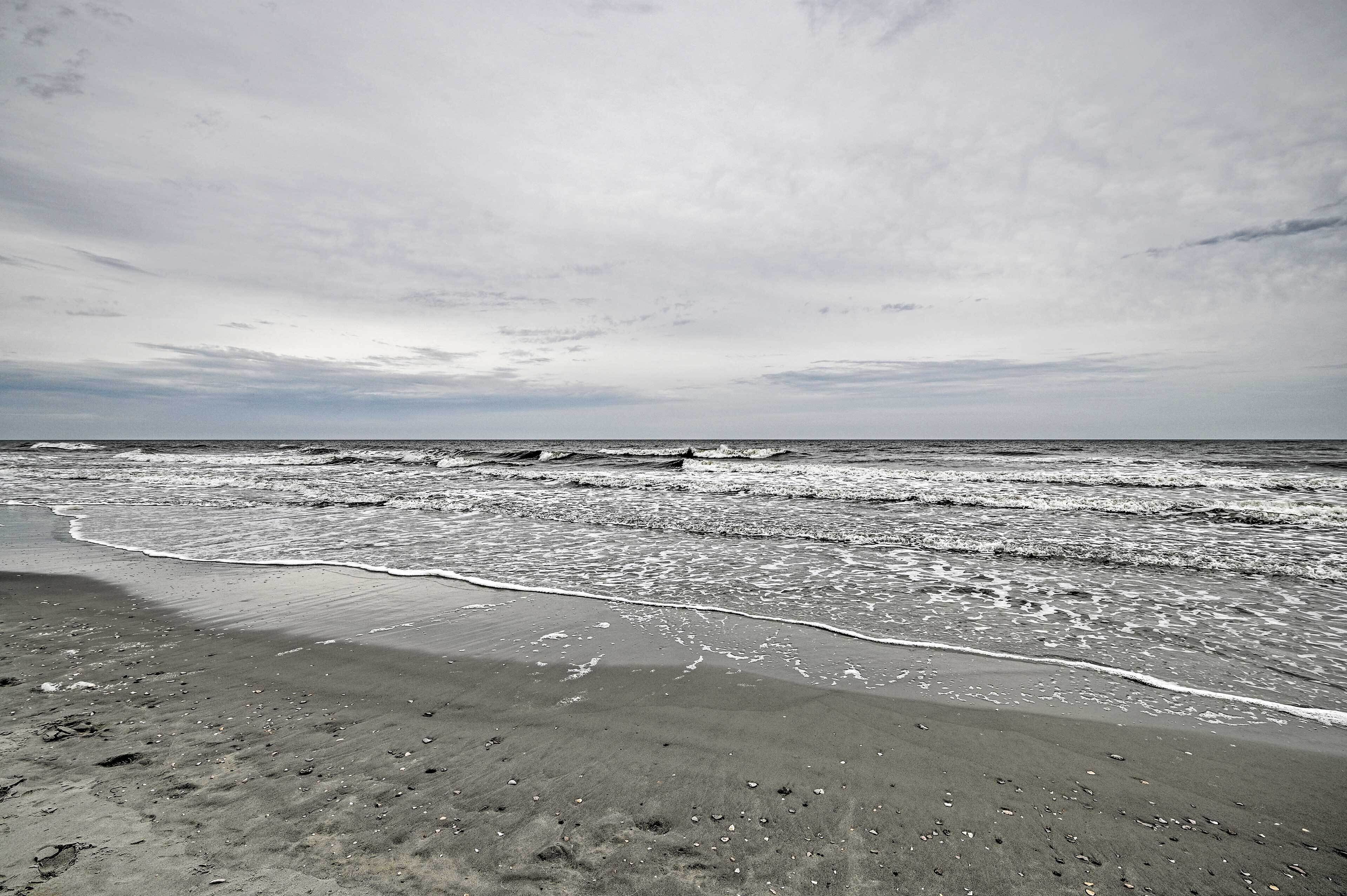 Ein Strand mit sanft rauschenden Wellen unter einem bewölkten Himmel.