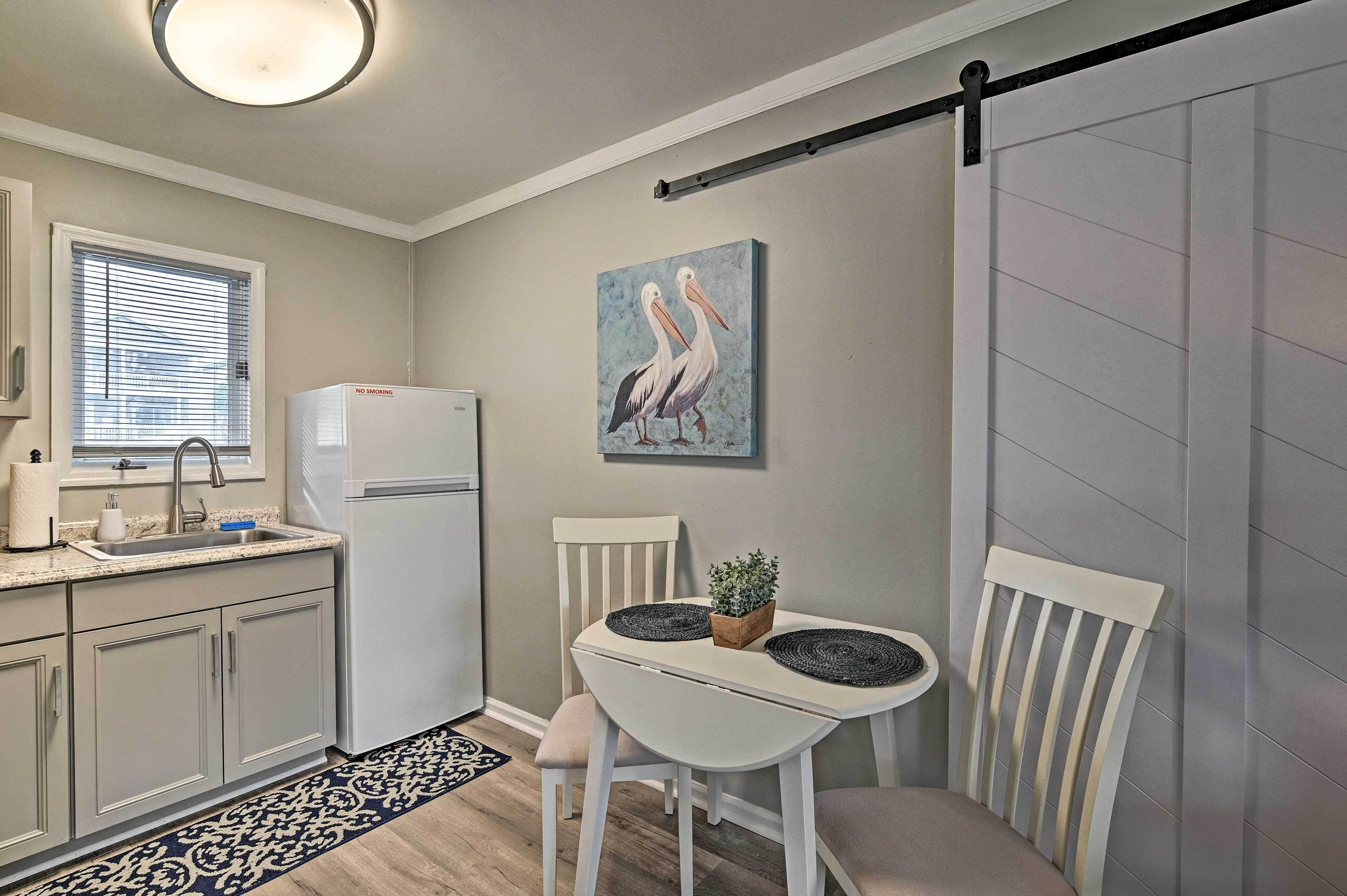 A compact kitchen with a sink, a refrigerator, and a dining area with a table and chairs.