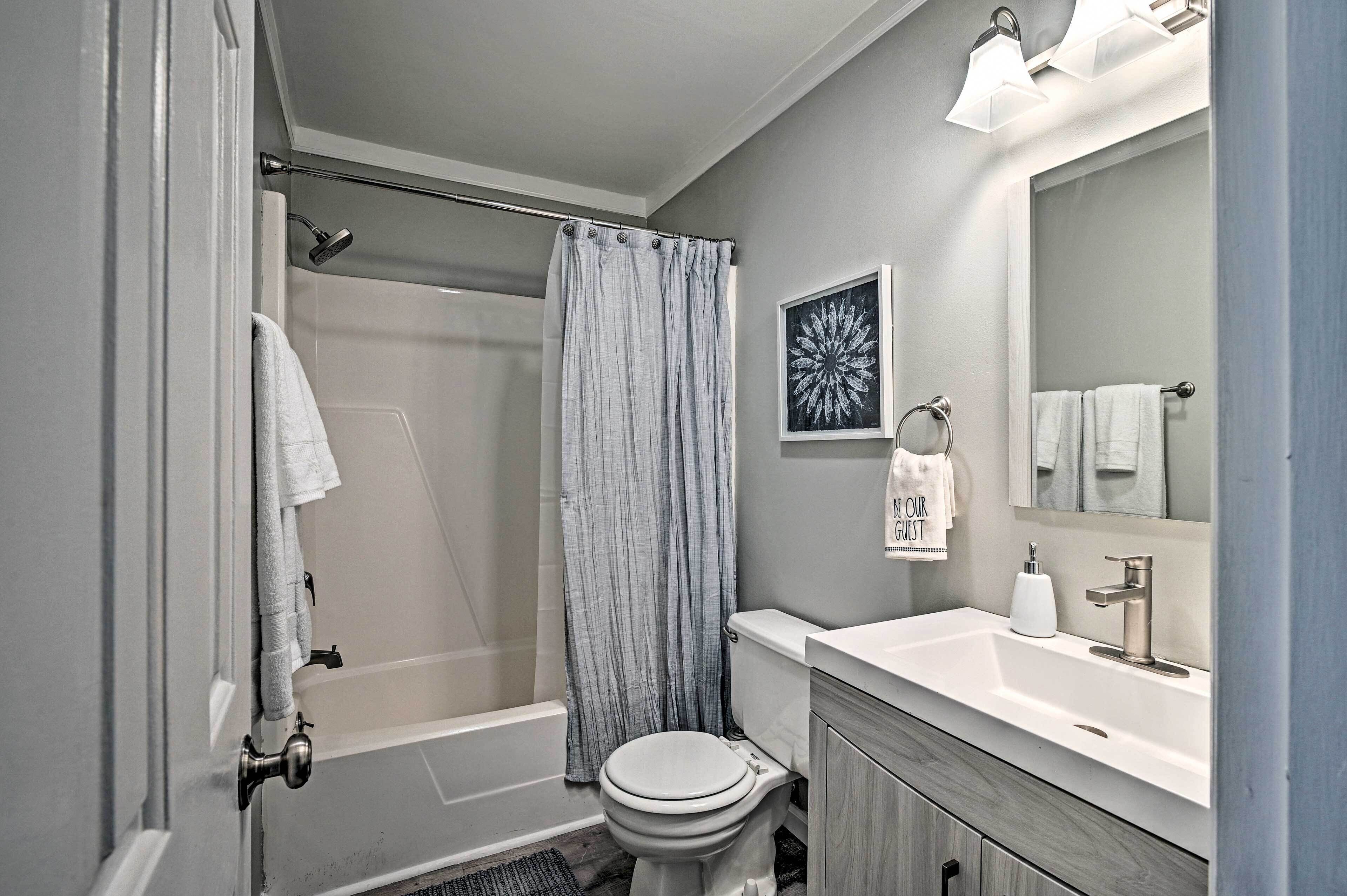 A modern bathroom with a shower, toilet, and sink.