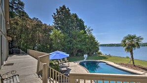 Una terraza con piscina, mobiliario exterior y vistas a un lago.
