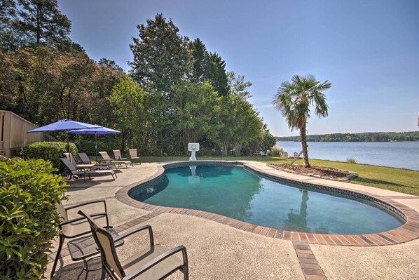 A swimming pool with a basketball hoop, lounge chairs, and a view of a lake. - Impeccable Home w/ Dock & Pool on Lake Wateree! (Camden)