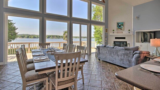 Un área de comedor con vistas a un lago, chimenea y un ventanal grande.