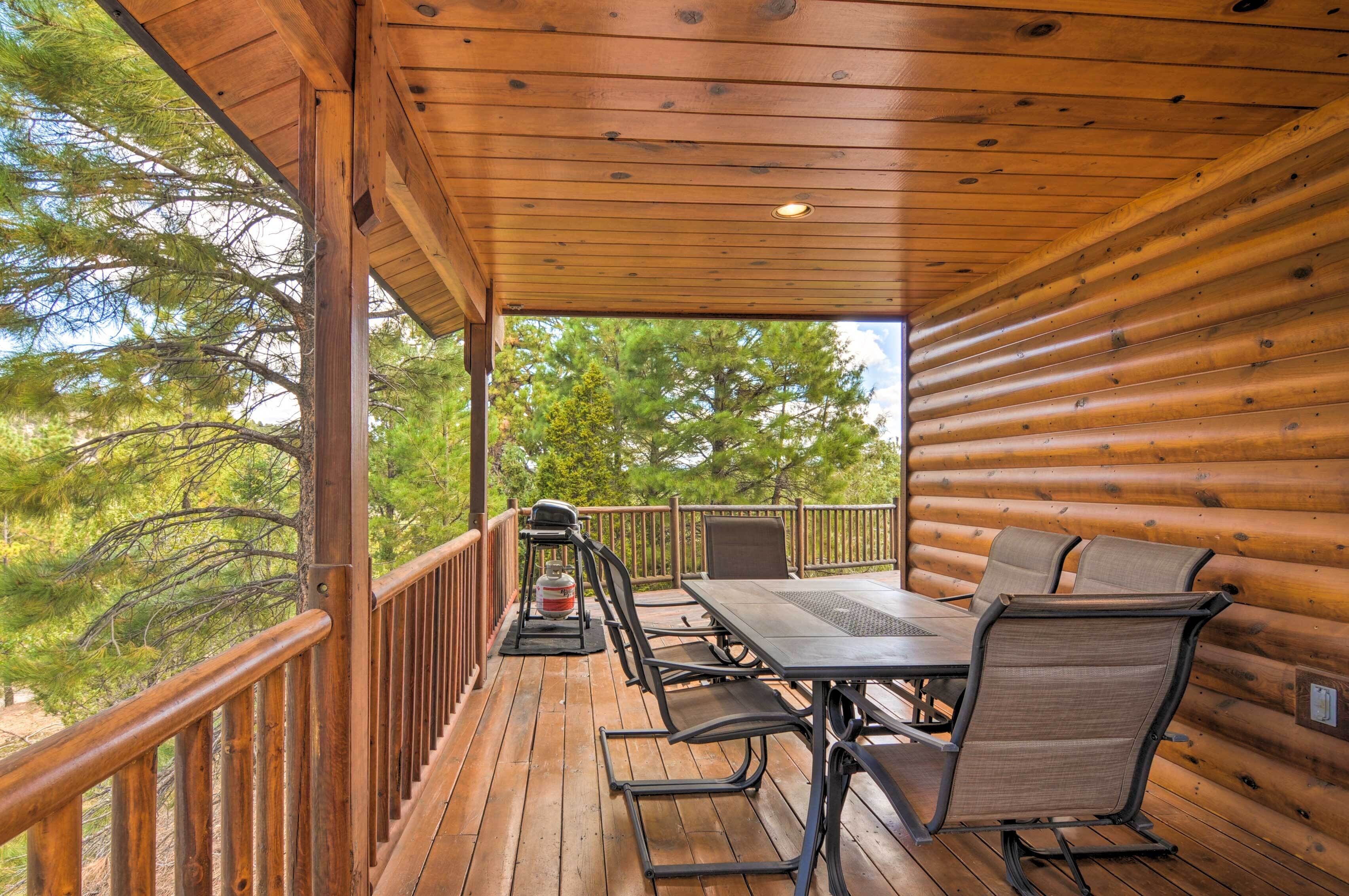 Eine Holzdielen-Terrasse mit Tisch und Stühlen mit Blick auf ein bewaldetes Gebiet.