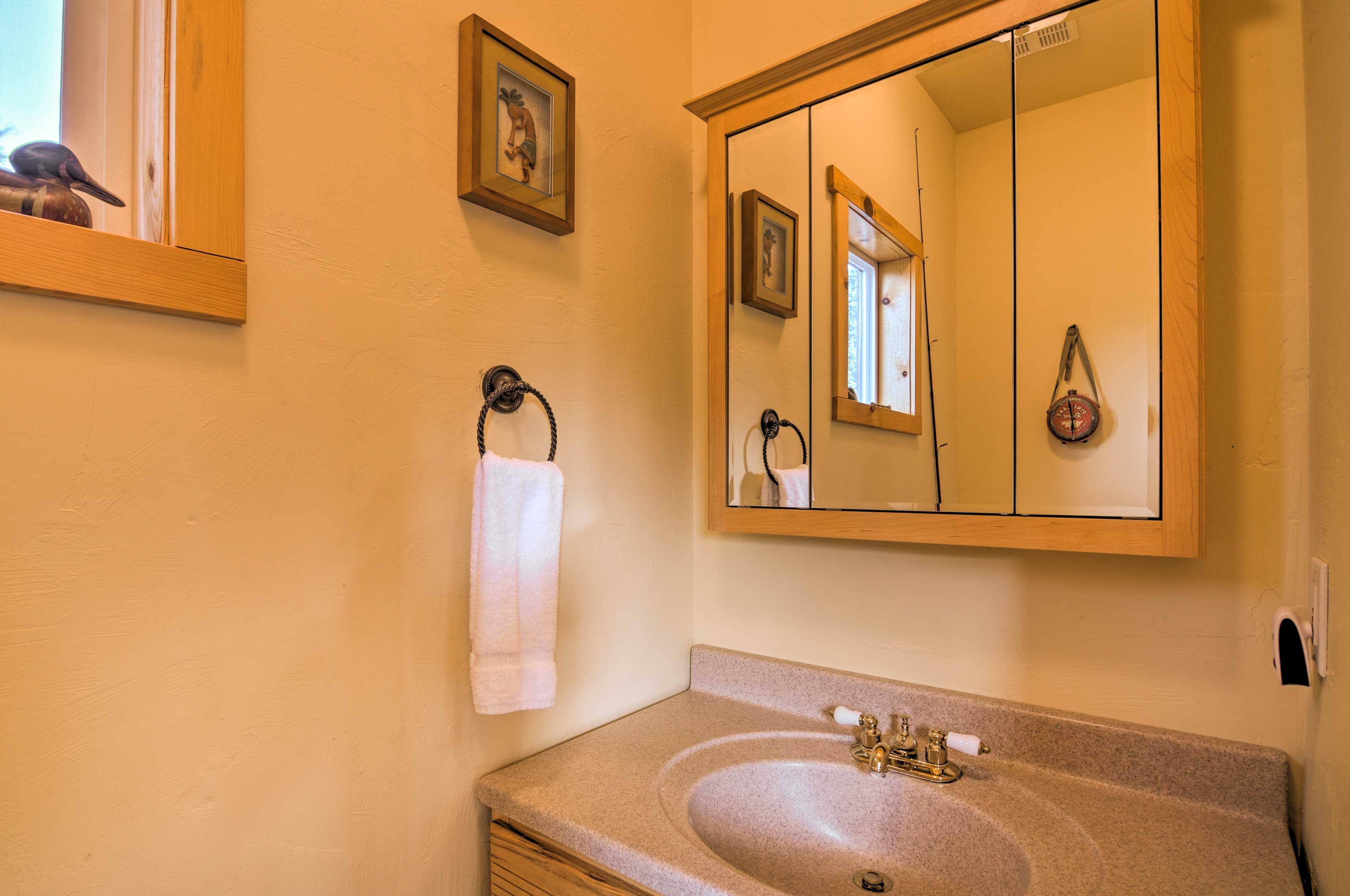A bathroom with a sink, mirror, towel rack, and framed pictures on the wall.
