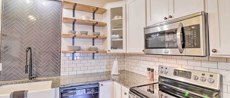 A modern kitchen with white cabinets, a stainless steel refrigerator, a microwave, and an oven.