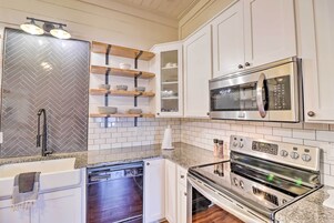 A modern kitchen with white cabinets, a stainless steel refrigerator, a microwave, and an oven.