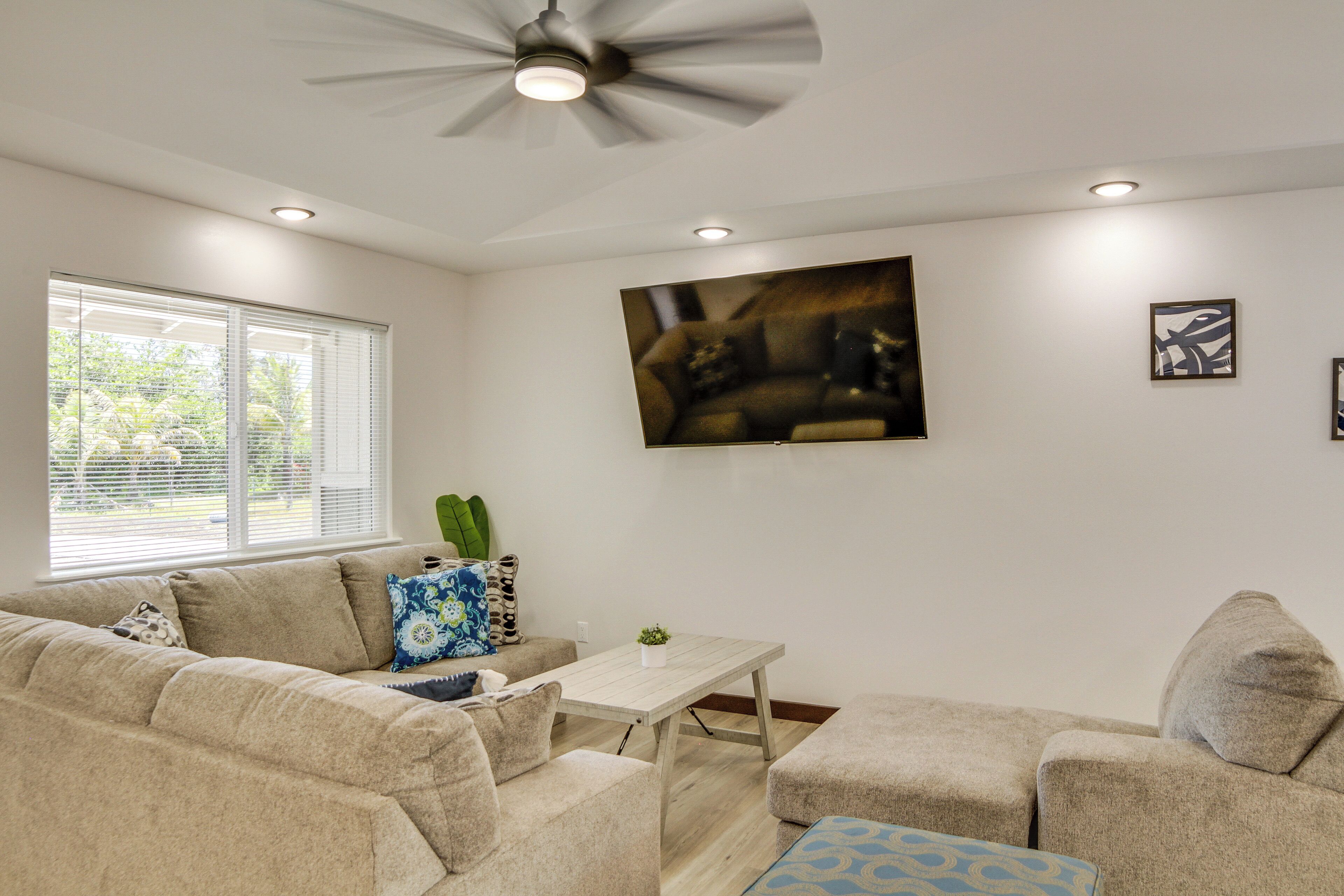 A living room with a beige sofa, a coffee table, and a ceiling fan.