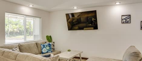 A living room with a beige sofa, a coffee table, and a ceiling fan.