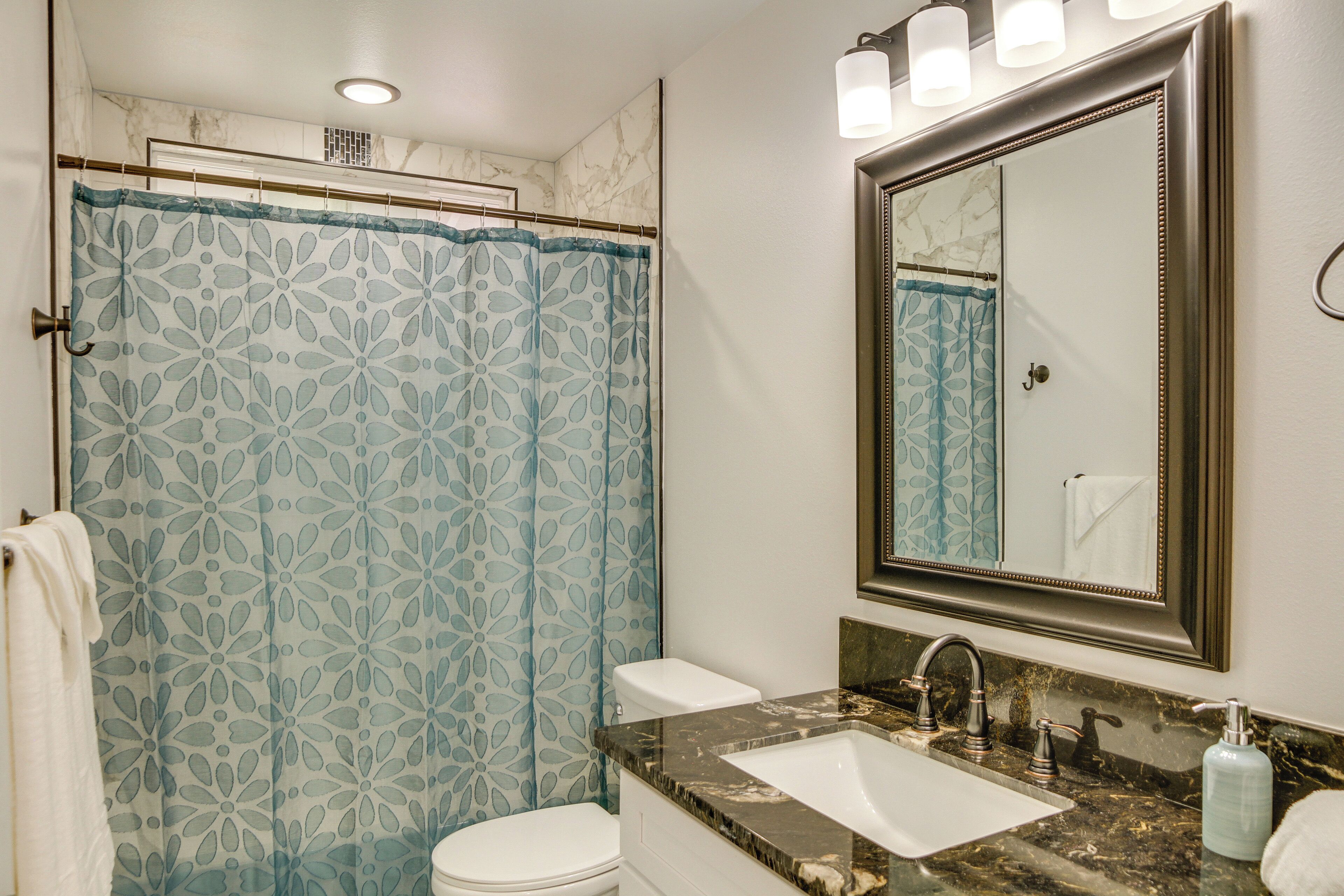 Une salle de bain équipée d’un rideau de douche, de toilettes, d’un lavabo et d’un miroir.