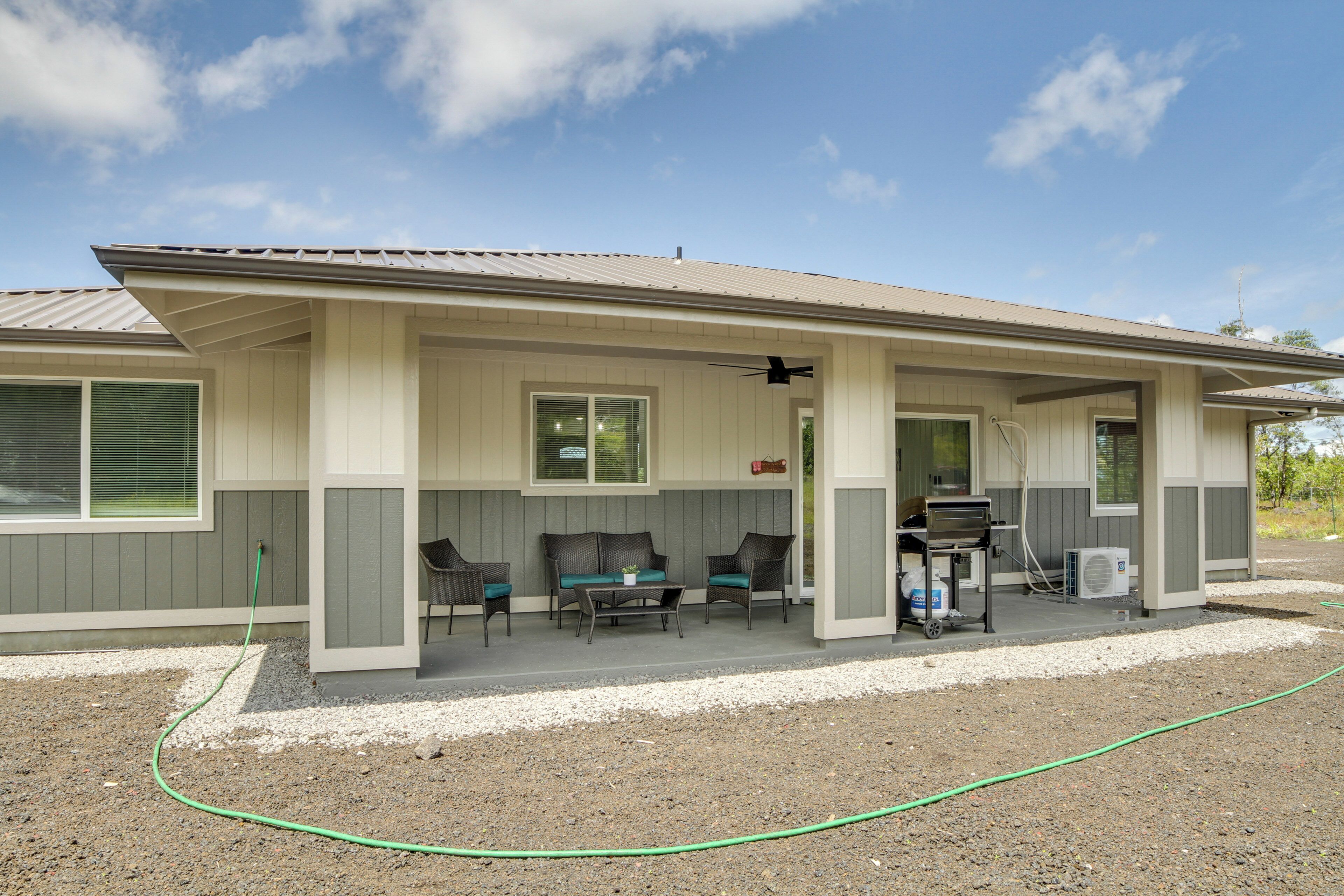 A single-story house with a covered porch, a grill, and a hose.