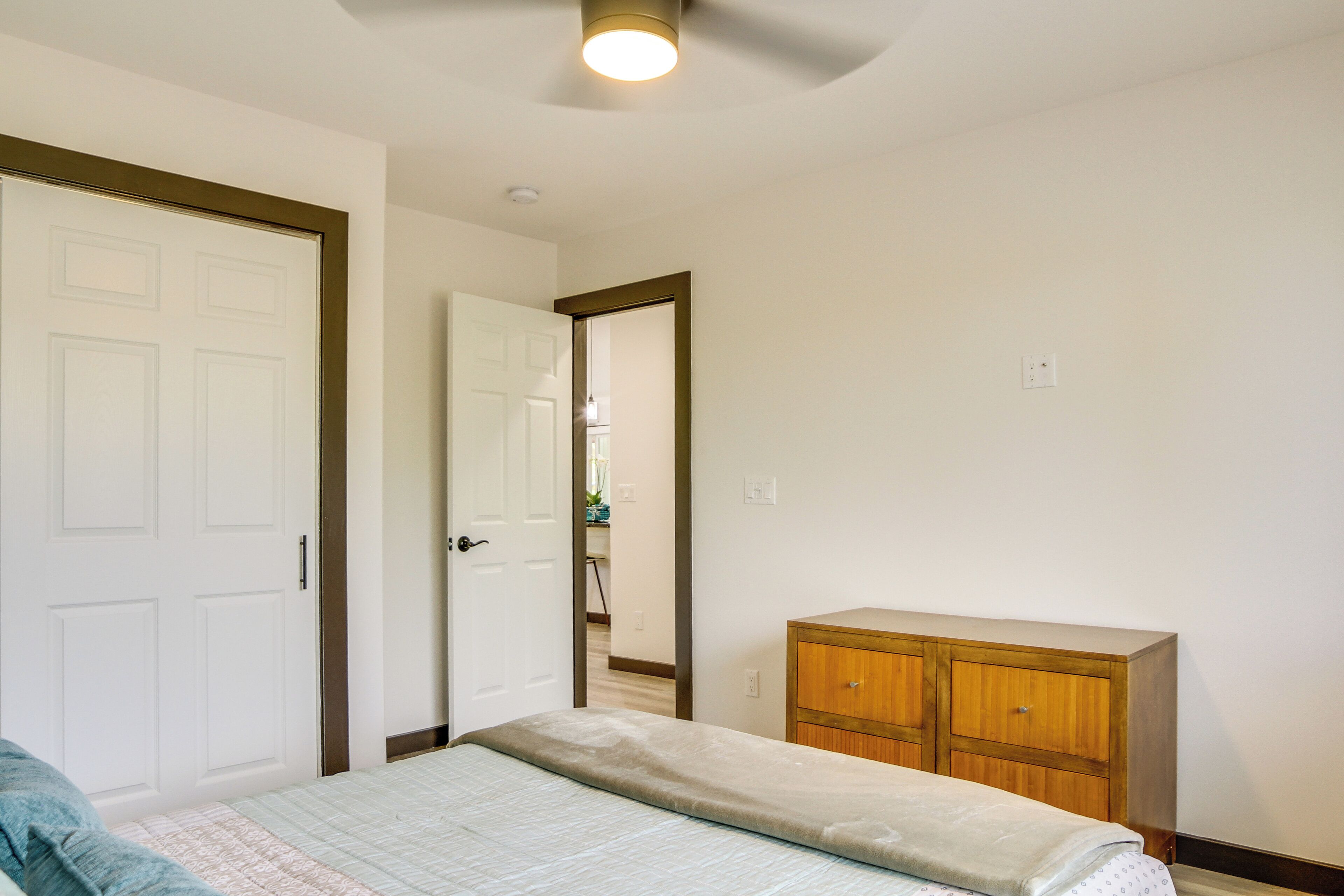 A bedroom with a bed, a wooden dresser, and a white door.
