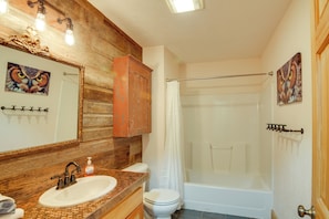 A bathroom with a wooden vanity, a white sink, a toilet, and a bathtub. - Rustic Pagosa Springs Cabin w/ Hot Tub + Game Room (Pagosa Springs)