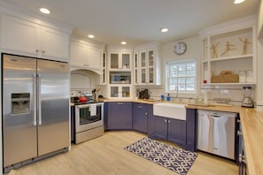 A modern kitchen with white cabinets, stainless steel appliances, and a patterned rug. - Historic Albion Mountain Cottage on Quiet Street! (Albion)